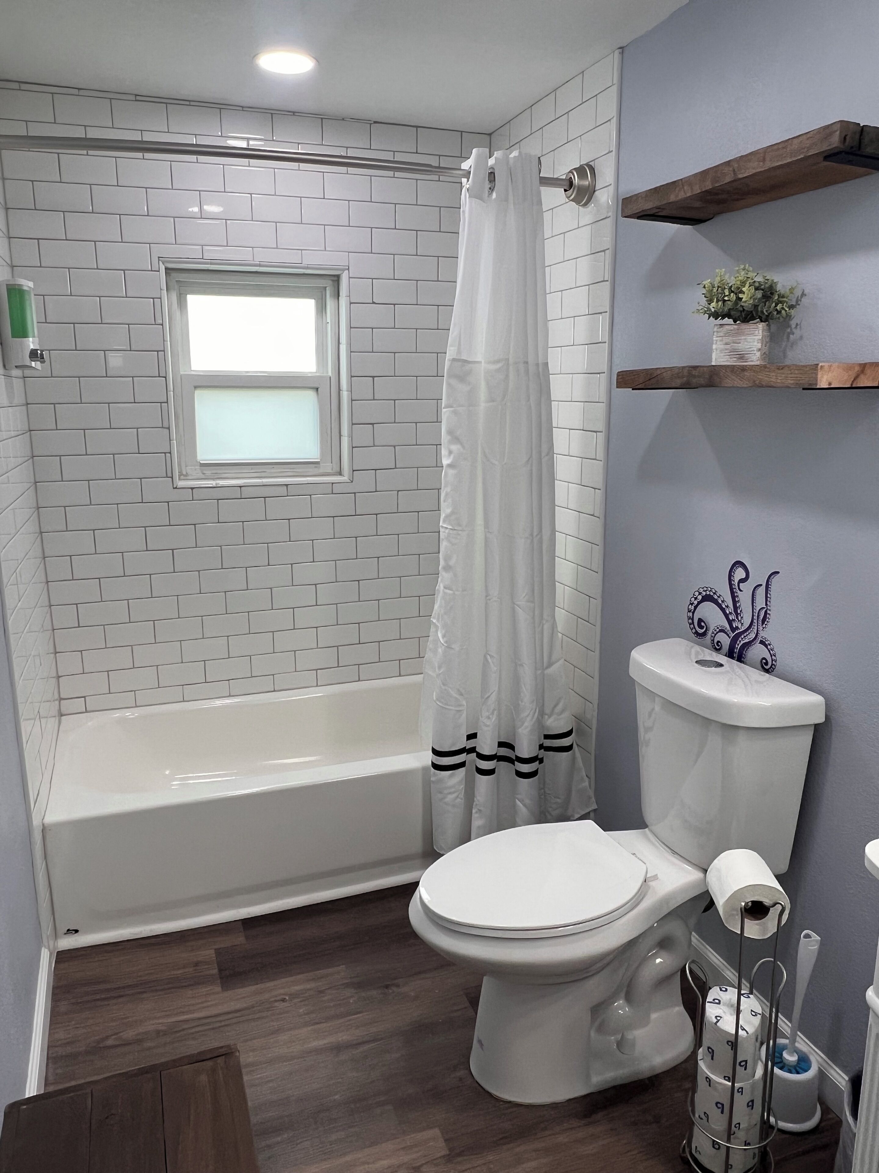 Une salle de bain avec une baignoire blanche, des toilettes et un rideau de douche.