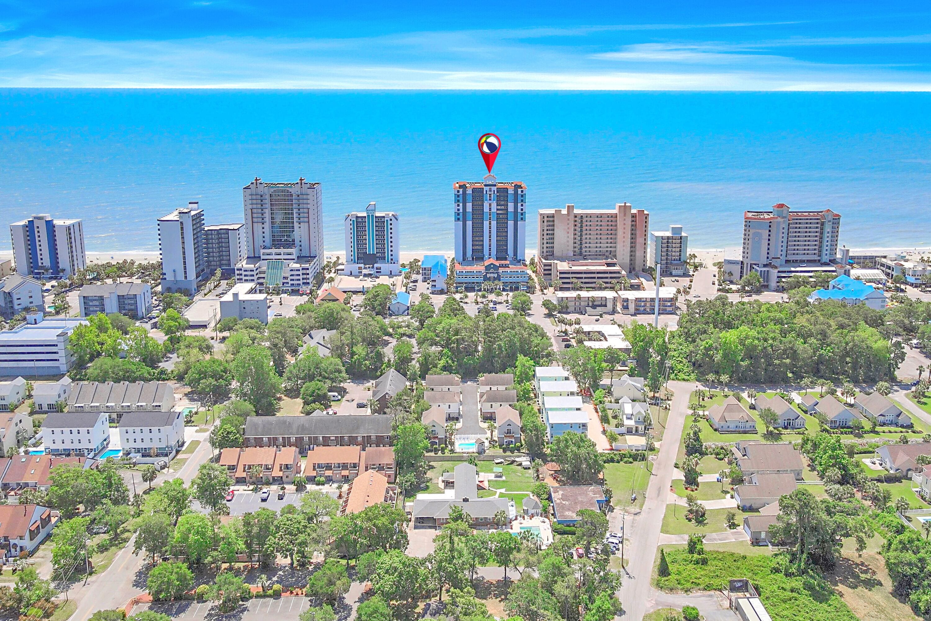 An aerial view of a coastal city with high-rise buildings, a beach, and a mix of residential and commercial structures.