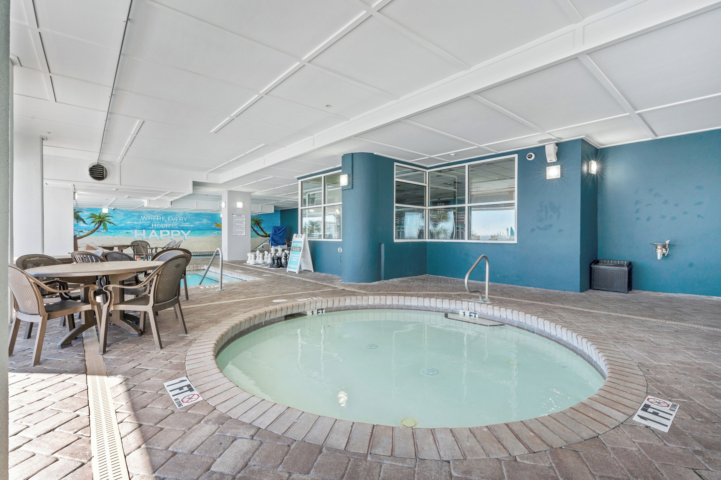 An indoor pool area with a pool, seating area, and a view of the city skyline.