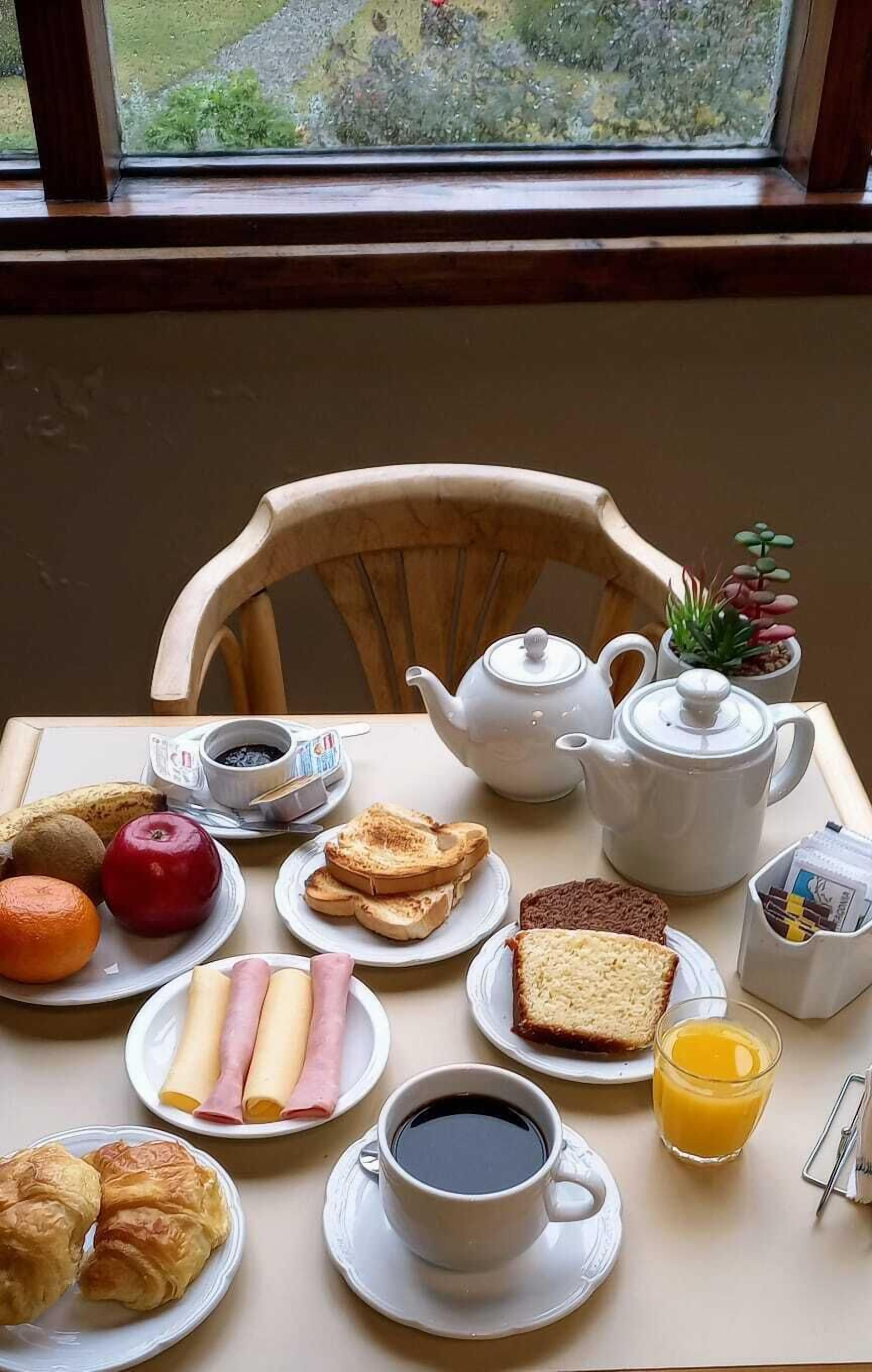 A breakfast table with various food items and a teapot.