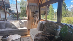 A cozy living room with a sofa, a coffee table, and a large window offering a view of the outdoors.