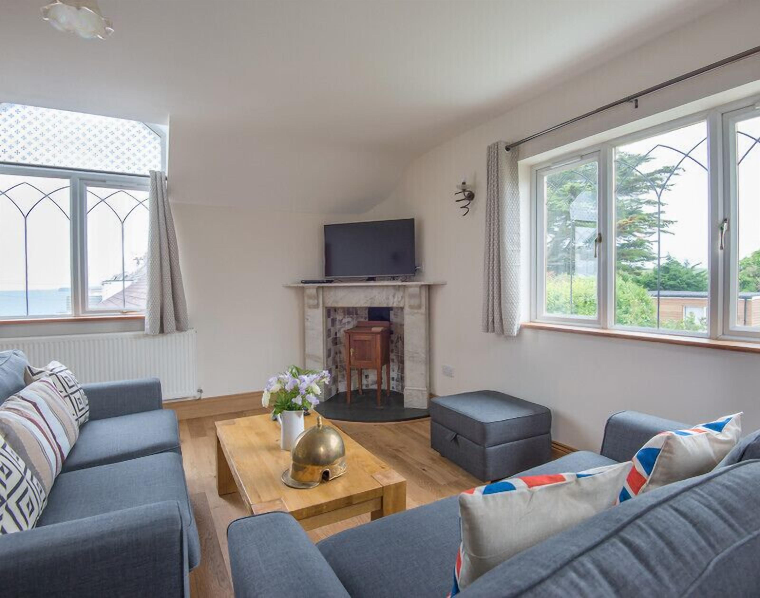 Una sala de estar con chimenea, sofás, una mesa de centro y ventanas amplias.