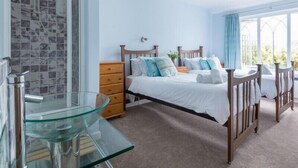 A bedroom with a glass table, wooden bed, and a view of the outdoors. - Fairholme (Port Isaac)