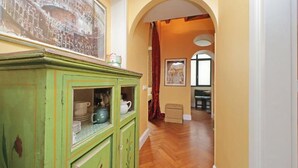 Un pasillo con un armario verde, un cuadro y un arco que da a un comedor.