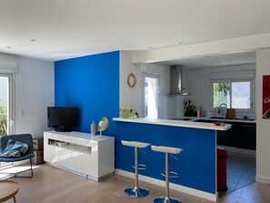 Una cocina moderna con una pared azul de acento, televisor integrado y una zona de bar con taburetes.