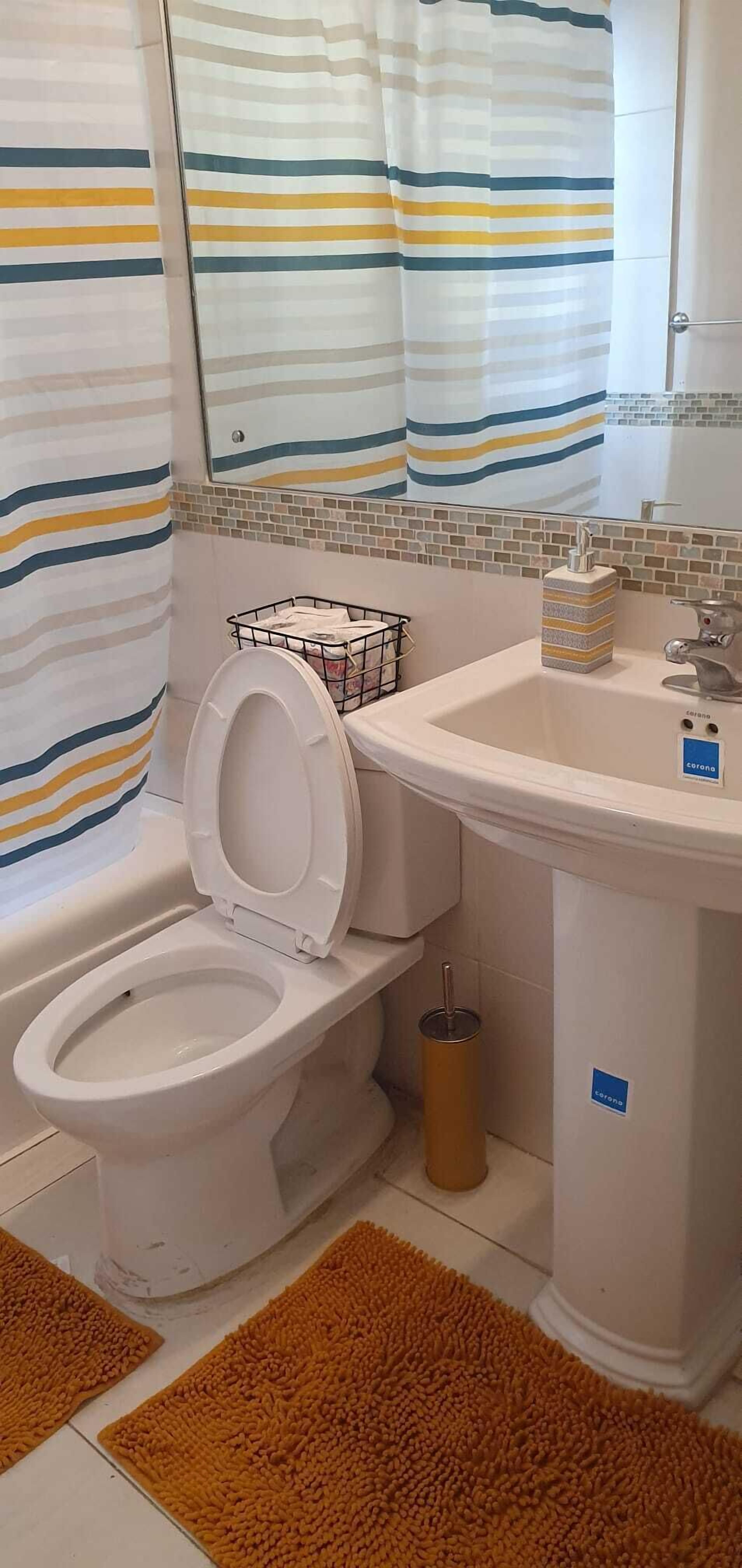 A bathroom with a toilet, sink, and shower curtain.
