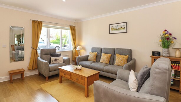 A living room with a sofa set, a coffee table, a side table with a lamp, and a mirror. - Inglewood (Keswick)