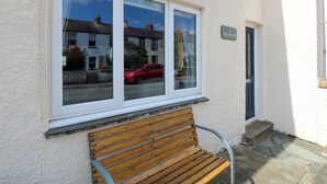 A white building with a wooden bench outside, a window reflecting a red car, and a door with a sign reading "4 Inglewood". - Inglewood (Keswick)