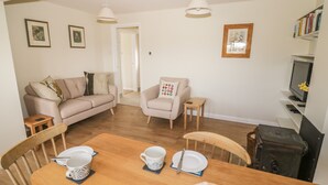 A living room with a sofa, armchair, dining table with chairs, and a television. - The Wash House (Banbury)