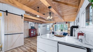 A spacious kitchen with wooden beams, a large island with drawers, and a view of the outdoors.