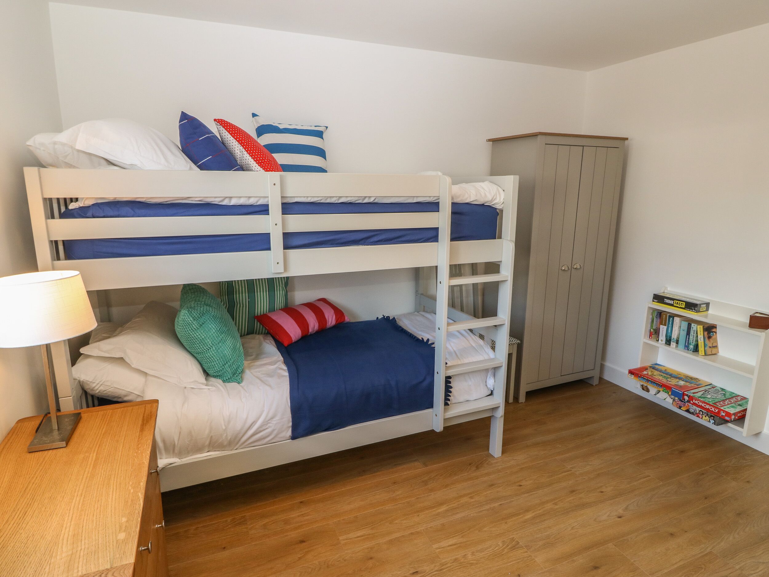 A bunk bed room with a desk, a cabinet, and a bookshelf.