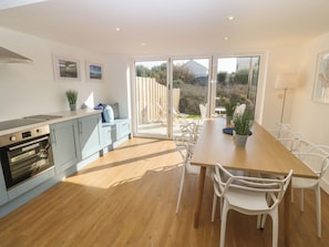 A modern kitchen with a dining area, large windows, and a view of the outdoors. - 3 Lon Y Dryw (Holyhead)