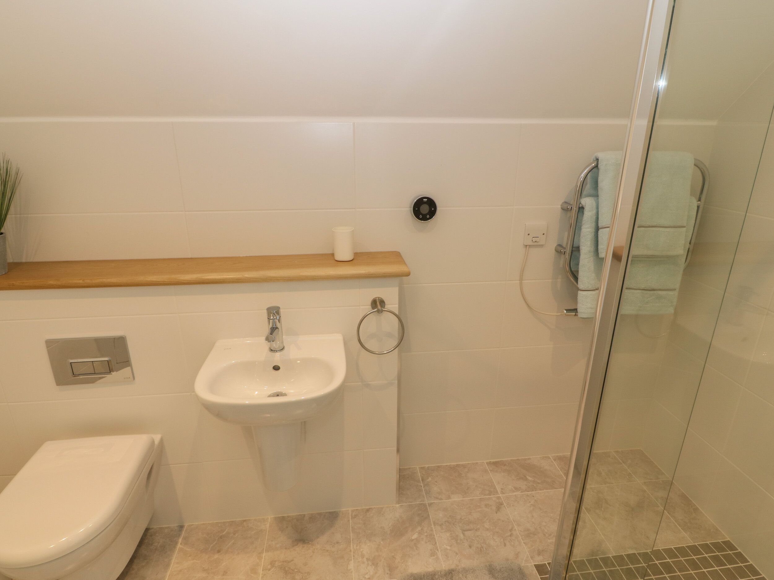A bathroom with a toilet, sink, and shower area.