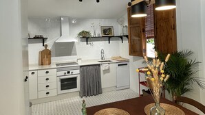 Una cocina moderna con armarios blancos, una mesa de comedor de madera y una lámpara colgante.