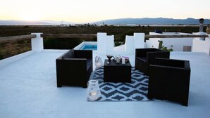 Terraço no telhado com piscina, móveis de exterior pretos e um tapete estampado.