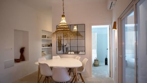 Uma sala de jantar moderna com uma mesa redonda, cadeiras brancas e um lustre decorativo.