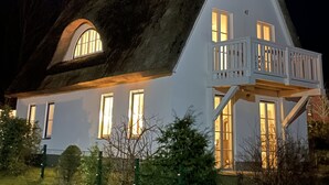 Ein Haus mit einem steilen Satteldach, einem Balkon mit Geländer und mehreren Fenstern.