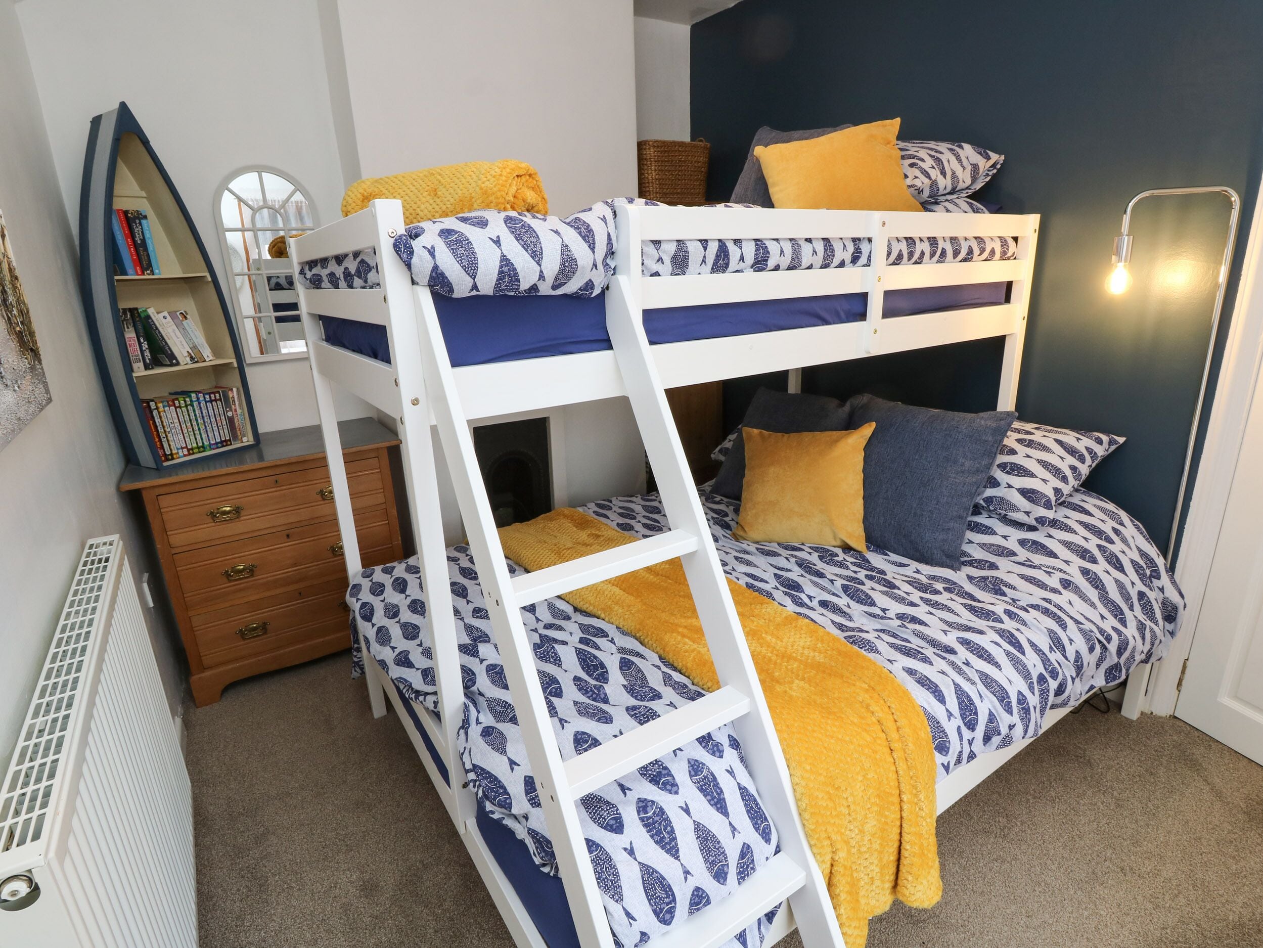 A bunk bed with a bookshelf and a dresser.