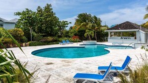 A swimming pool with blue lounge chairs and a small pavilion. - Villa Stingray, Family-Sized Condo-5 minutes from the beautiful beach! (Providenciales)