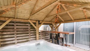 A wooden deck with a hot tub, wooden slats, and string lights. - Fistral Apres Surf (Newquay)