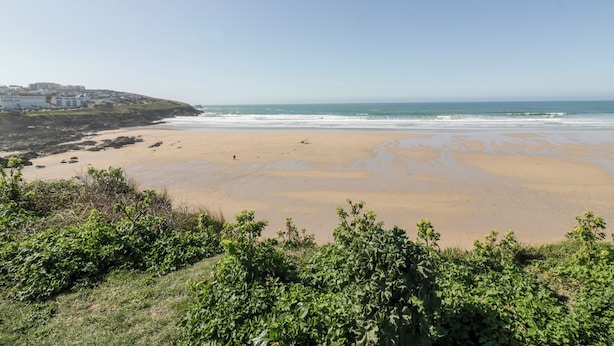 A coastal beach with a clear view of the ocean and a distant town. - Fistral Apres Surf (Newquay)