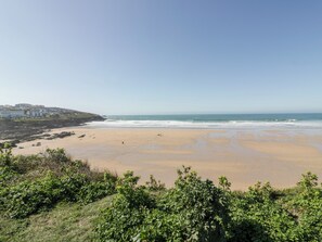 A coastal beach with a clear view of the ocean and a distant town.
