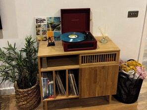 A wooden music player with a red cover, a woven basket with books, and a small plant. - Fistral Apres Surf (Newquay)