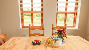 A wooden dining table with a plate of strawberries and two yellow cups, a blue and white teapot, and a pitcher on a tray. - Daisy's Cottage (Knockreagh)