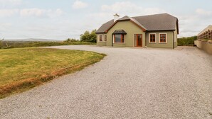 A single-story house with a gravel driveway, a chimney, and a small porch. - Daisy's Cottage (Knockreagh)