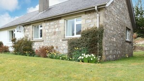 A stone house with a sloped roof, white windows, and a chimney. - Ben Grianan (Aberfeldy)