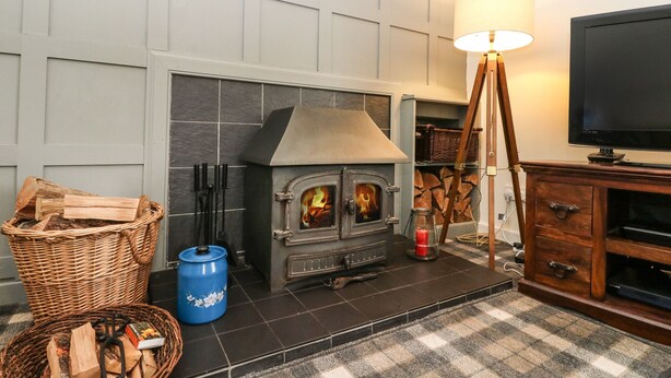A cozy living room with a fireplace, a television, and a lamp. - Ben Grianan (Aberfeldy)
