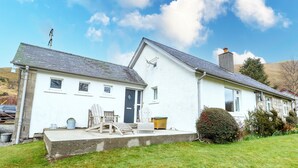 A two-story white house with a small porch, a chimney, and a satellite dish. - Ben Grianan (Aberfeldy)