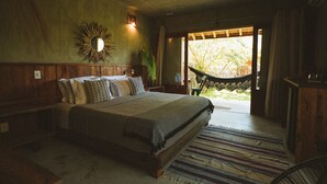 A bedroom with a bed, pillows, a wall-mounted mirror, and a view through a door. - Pousada Haya (São Miguel dos Milagres)
