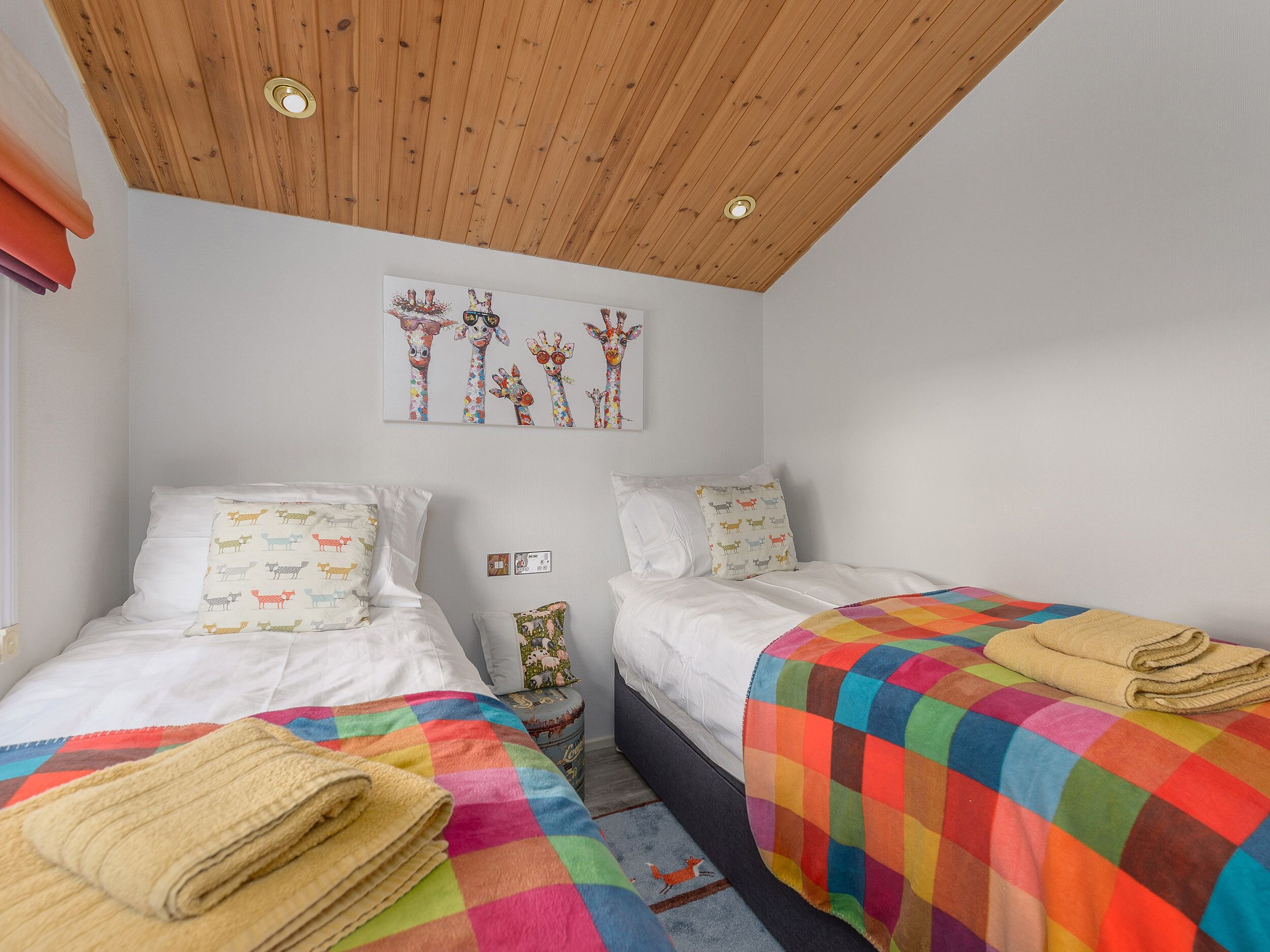 Ein Schlafzimmer mit zwei Betten, einer Holzbalkendecke und einer bunten Decke.