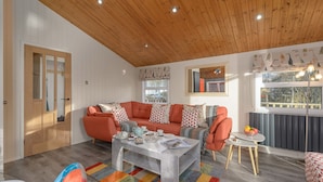 Uma sala de estar aconchegante com teto de madeira, um sofá, uma mesa de centro e uma janela com vista para o exterior.