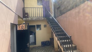 Uma passagem estreita com uma escadaria que leva a uma varanda no segundo andar.