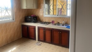 A kitchen with a microwave, stove, sink, and cabinets. - Manoir des Princesses Ekoumdoum (Yaoundé)
