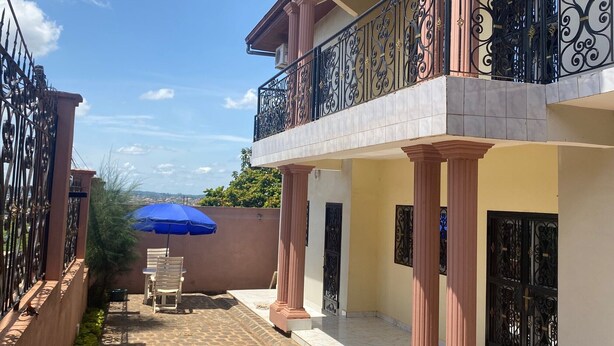 A residential building with a balcony, tiled flooring, and a blue umbrella. - Manoir des Princesses Ekoumdoum (Yaoundé)