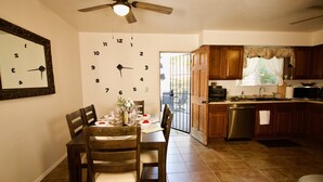 A kitchen with wooden cabinets, a dining table set for four, and a wall clock. - 3 blks to Historic downtown Courthouse & Whiskey Row. King bed. Dog Friendly (Prescott)