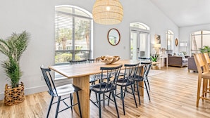 Un comedor con una mesa de madera, sillas negras y una lámpara colgante de fibras naturales.