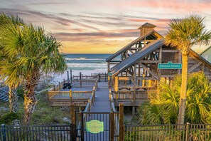 A wooden boardwalk leading to a beach pavilion with a sign reading "Emerald Shores."