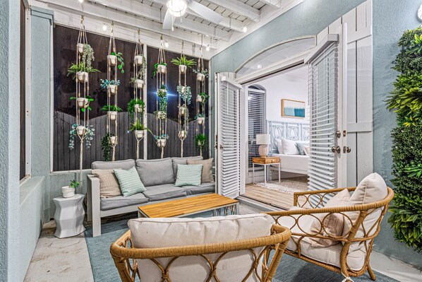 A cozy indoor seating area with a sofa, wicker chairs, and hanging planters.