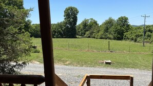 Una terraza de madera con un sendero de grava que lleva a un campo cercado.