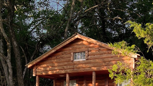 Una cabaña de madera con un porche y una escalera que lleva a una terraza.
