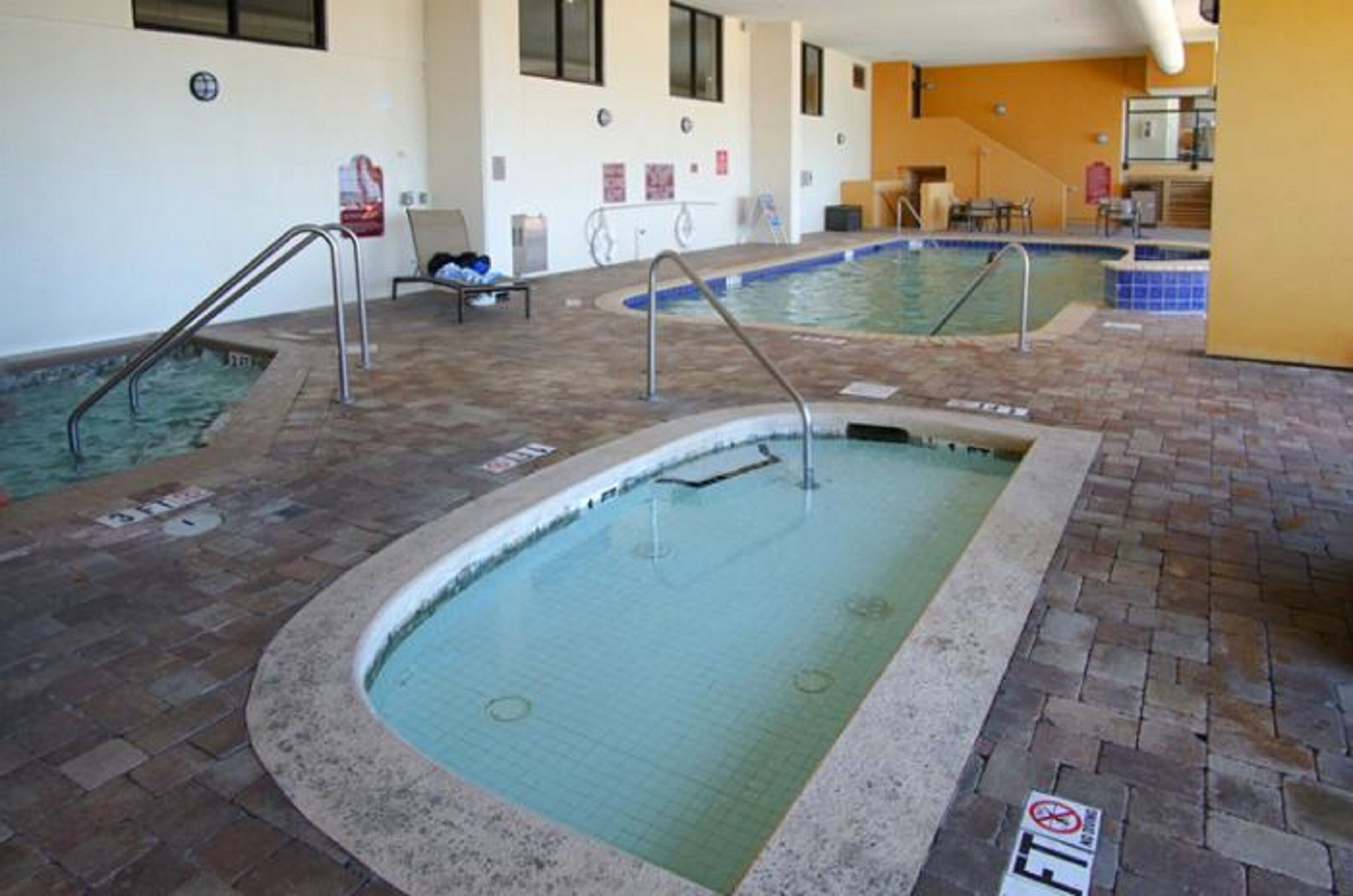 An indoor swimming pool with multiple lanes, a changing room, and a reception area.