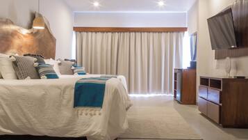 A modern bedroom with a large bed, a ceiling fan, a TV, and a wooden cabinet.
