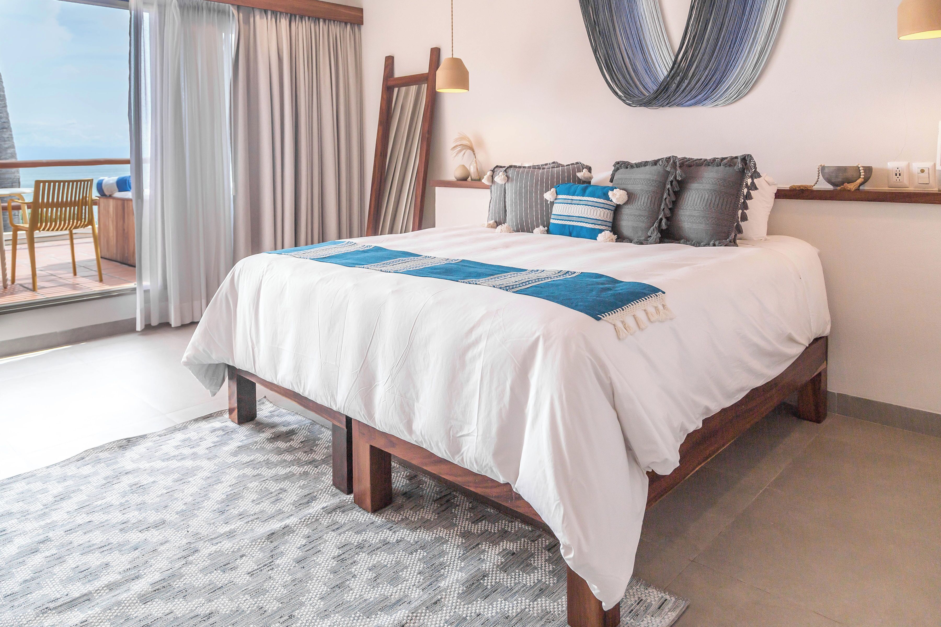 Ein Schlafzimmer mit einem großen Bett, Meerblick, einem Holzstuhl und einer Hängematte.