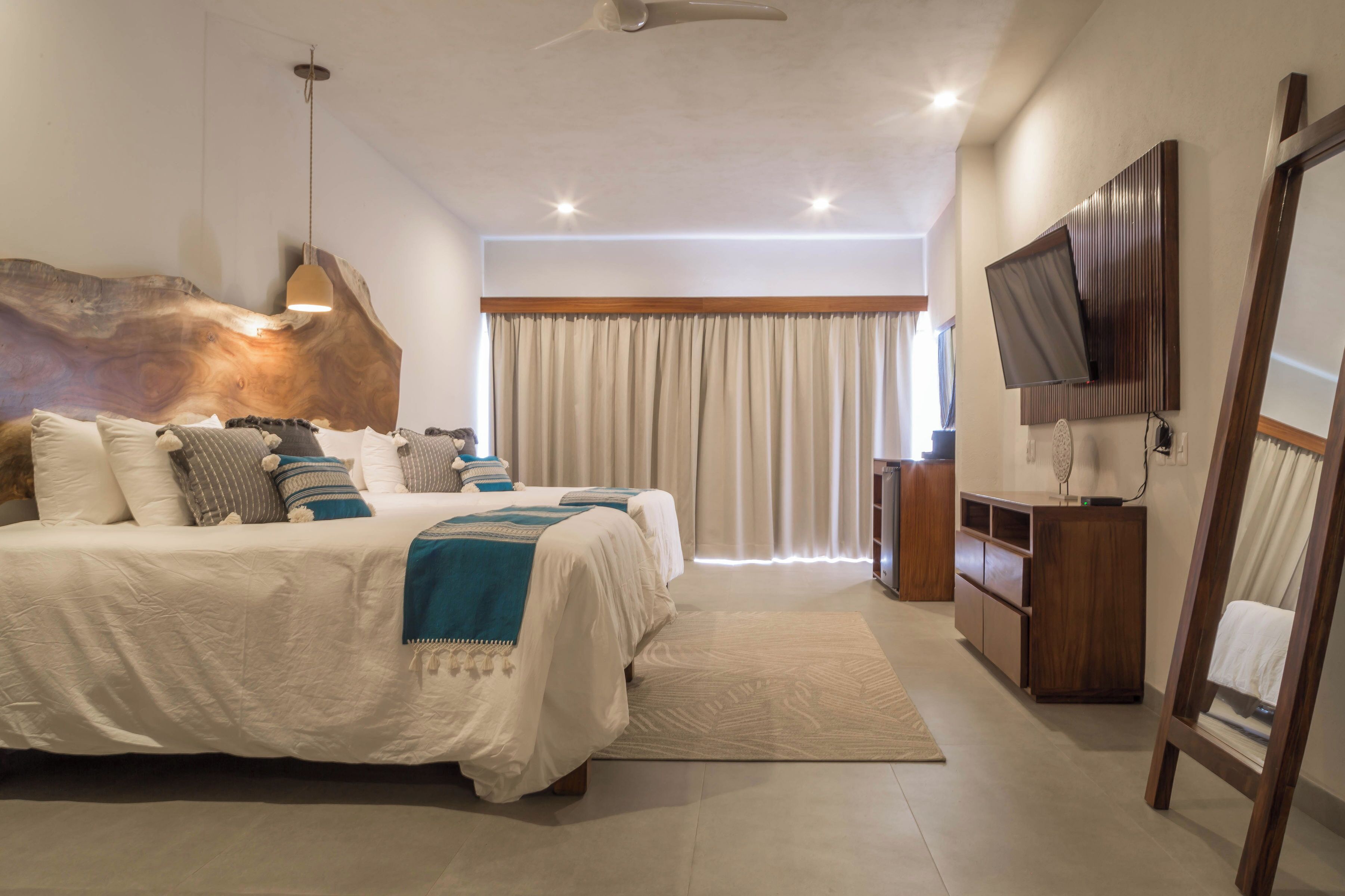 Un dormitorio moderno con una cama grande, cabecera de madera, televisor y un escritorio con silla.