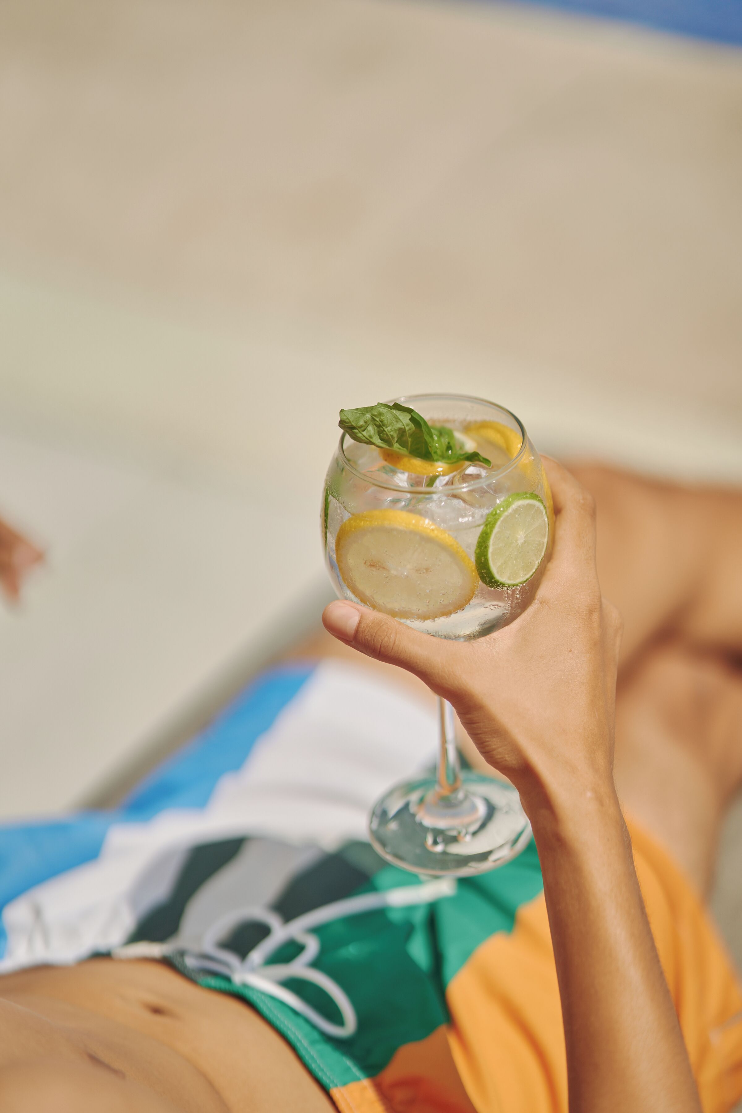 A person holding a glass with a beverage, wearing a colorful shirt.