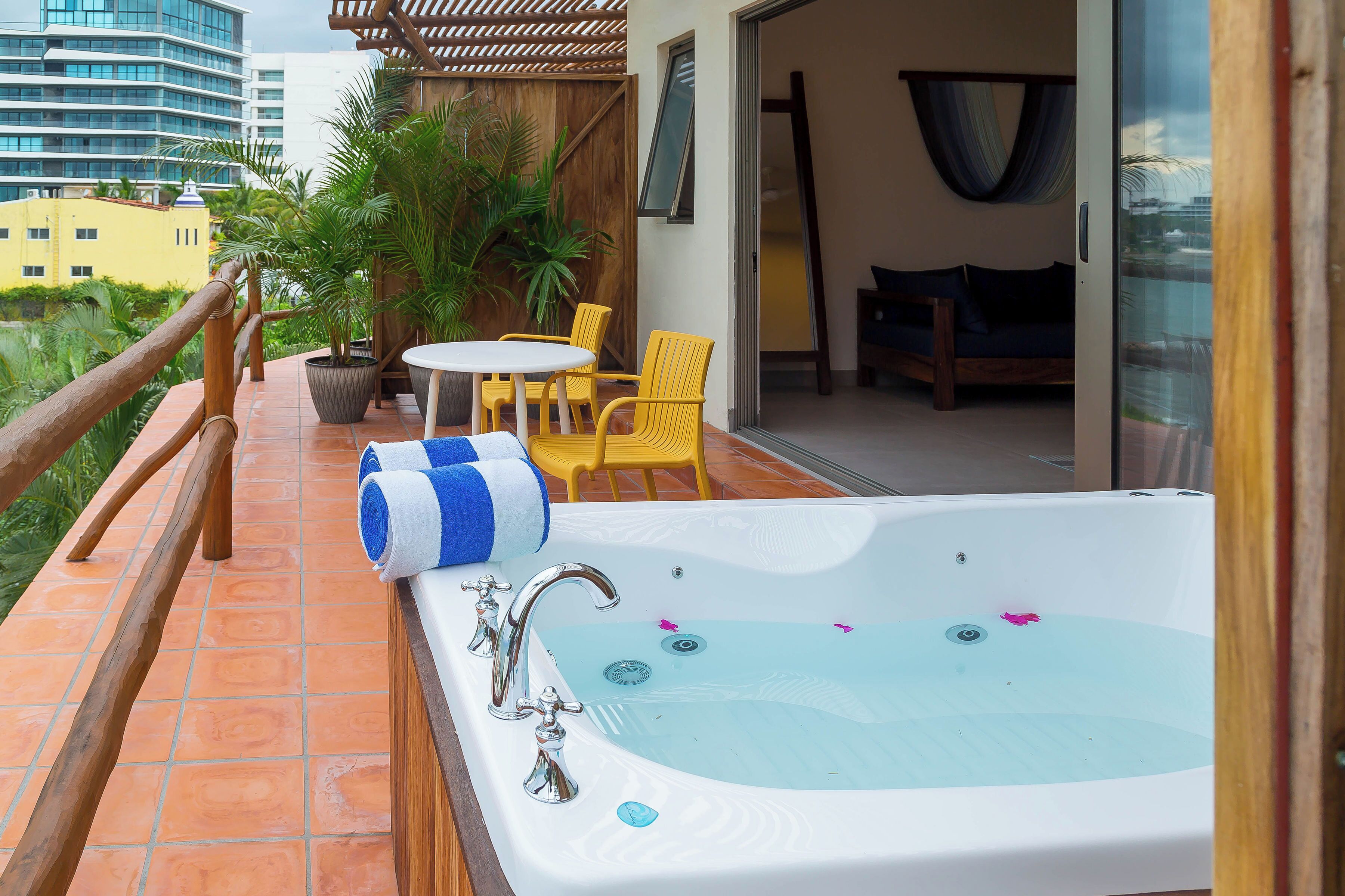 A balcony with a hot tub, yellow chairs, and a wooden railing.